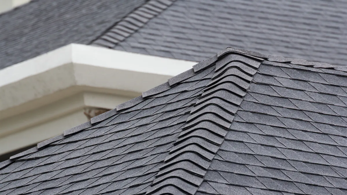 Close-up of shingle ridge installation showing ridge cap course and proper lap pattern